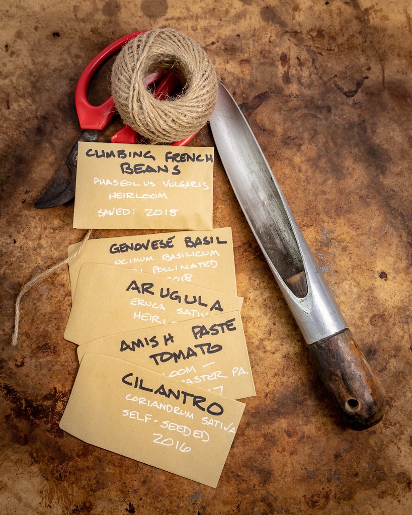 Handwritten seed packets beside twine and a metal scoop
